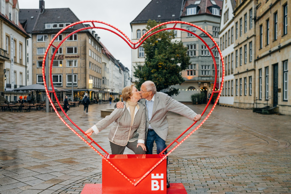 eine älteres Pärchen küsst sich umrahmt von einem Herz