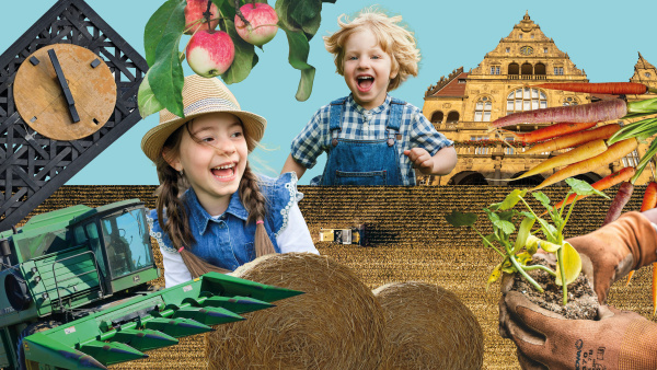 Kinder mit Strohhut spielen mit Heuhaufen und Bauernhofutensilien vor Bielefelder Wahrzeichen