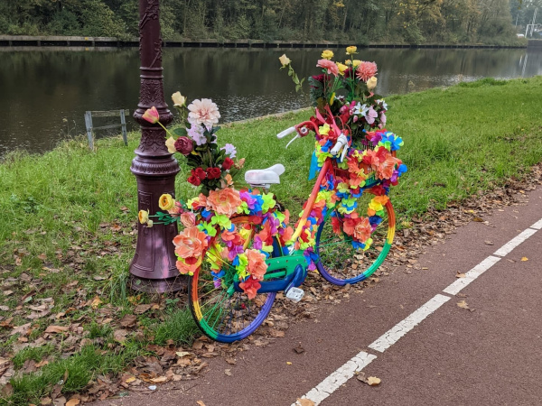 Fahrrad mit bunten Blumengirlanden am Straßenrand dekoriert.