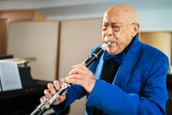 Giora Feidman spielt Flöte in blauem Hemd.