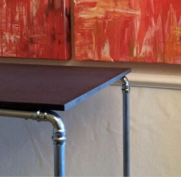 Azschnitt von Tisch mit viereckiger schwarzer Platte und Stahlrohrgestell aus Heizungsrohren