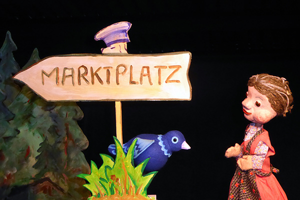 Kaspers Oma mit einem Vogel auf dem Marktplatz