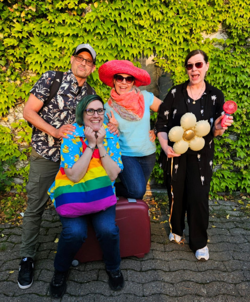 Vier Personen mit Urlaubsgepäck und Sommerklamotten.